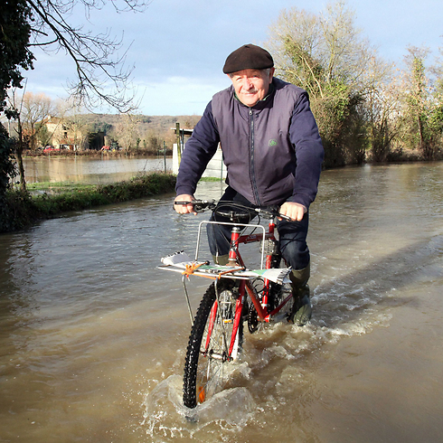 אדם רוכב על אופניו בשביל מוצף בכפר קקסון שבצרפת לאחר שגשמים כבדים ירדו במקום (צילום: AFP) (צילום: AFP)