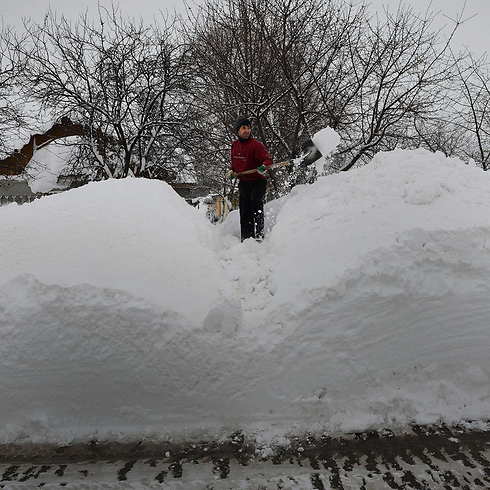 תושב הכפר סמיני שברומניה מפנה שלג בכניסה לביתו. שלג כבד גרם לסגירת שלוש דרכים בין-עירוניות במערב ובמזרח המדינה, השבית את התנועה האווירית ושיתק כ-20 קווי רכבת (צילום: AFP) (צילום: AFP)