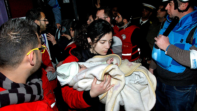 עובדת "הסהר האדום" מפנה תינוק מחומס (צילום: AP) (צילום: AP)