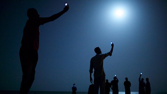 טלפון לכל אחד. תמונת השנה 2014 הגיעה מאפריקה: מהגרים בדרך לאירופה מניפים את הטלפונים הסלולריים שלהם בניסיון למצוא קליטה ולהתקשר הביתה (צילום: AFP) (צילום: AFP)