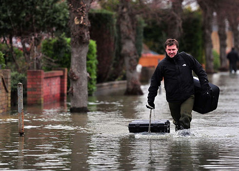 מזג האוויר הסוער בבריטניה לא הותיר מקום אחד יבש. אדם מפלס את דרכו בכביש מוצף בכפר סטיינס ממערב ללונדון (צילום: AFP) (צילום: AFP)