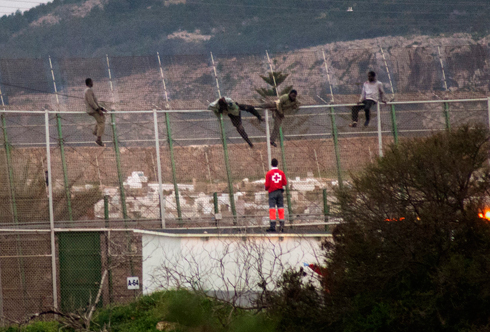 רגע של בריחה: מסתננים על הגדר, איש הצלב האדום מחכה כדי לסייע להם מעברה השני (צילום: AP) (צילום: AP)