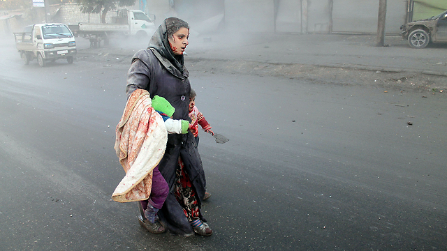 אשה סורית מובילה את ילדיה הרחק מחלב המופגזת (צילום: AFP) (צילום: AFP)