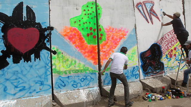 אמנים מציירים על אחד ממחסומי הבטון שהקימו כוחות הביטחון (צילום: AFP) (צילום: AFP)
