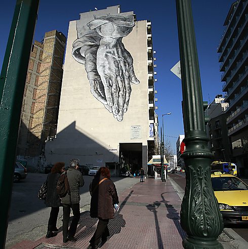 תמונת ידיים המעטרת בניין במרכז אתונה צוירה על-ידי פבלוס צאקונאס             (צילום: AP) (צילום: AP)