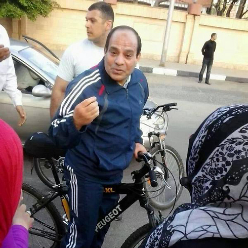 ספורטיבי. א-סיסי רוכב על אופניים ועוצר לשוחח עם תושבים בקהיר ()