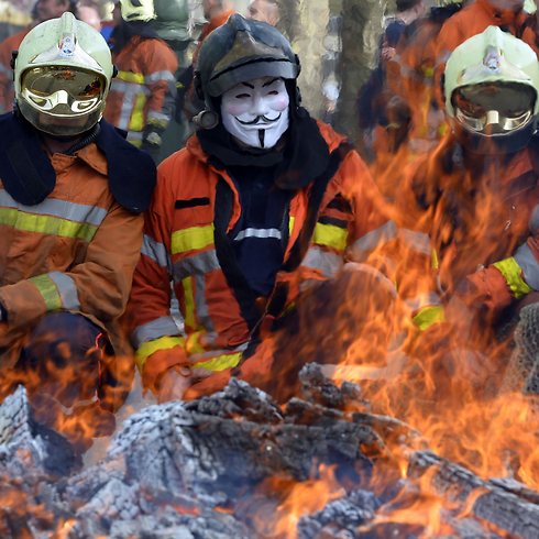 כבאים בבריסל מפגינים נגד הממשלה במחאה על תנאי שכרם לצד אש שהציתו במקום (צילום: AFP) (צילום: AFP)