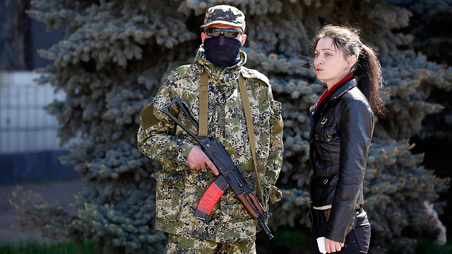 חמוש פרו-רוסי משוחח עם אישה ליד בניין השלטון המקומי שנכבש בעיר קוסטינטיניבקה (צילום: רויטרס) (צילום: רויטרס)