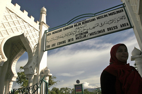 שלט בבנדה אצ'ה שמייעץ לנשים ללבוש בגדים איסלאמיים (צילום: AP) (צילום: AP)