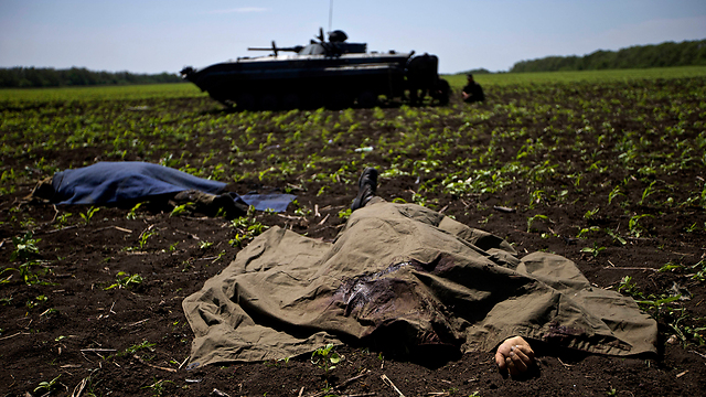 גופות חיילים על רקע משוריין אוקראיני (צילום: AP) (צילום: AP)