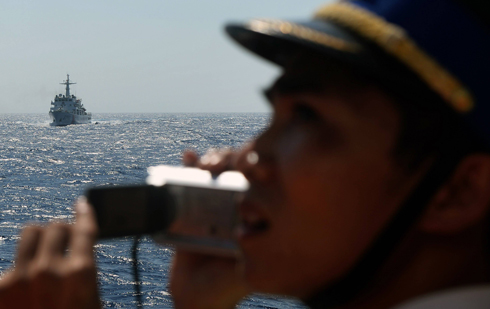 איש משמר החופים של וייטנאם בים סין הדרומי על רקע ספינת חיל ים סינית (צילום: AFP) (צילום: AFP)