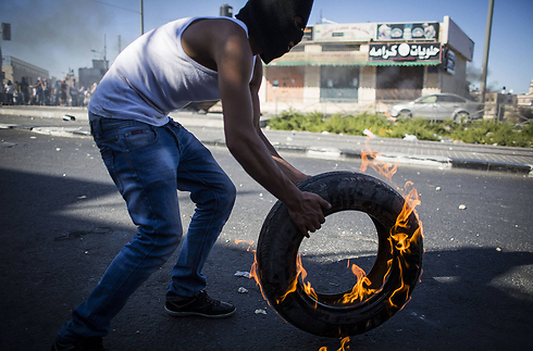 Masked Arab youth throwing a burning tire during clashes with Israel Police in East Jerusalem neighborhood of Shuafat (Photo: Gettyimages)