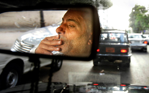 זה עולה לו ביוקר. נהג מונית מצרי מעשן סיגריה שגם מחירה רשם עלייה (צילום: AP) (צילום: AP)