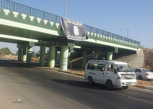 רכב חולף על פני דגל דאעש בעיר מוסול שבעיראק (צילום: AP) (צילום: AP)