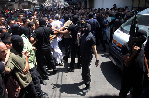 חמושי חמאס מרחיקים מעט את הקהל לפני ההוצאה להורג (צילום: AFP) (צילום: AFP)
