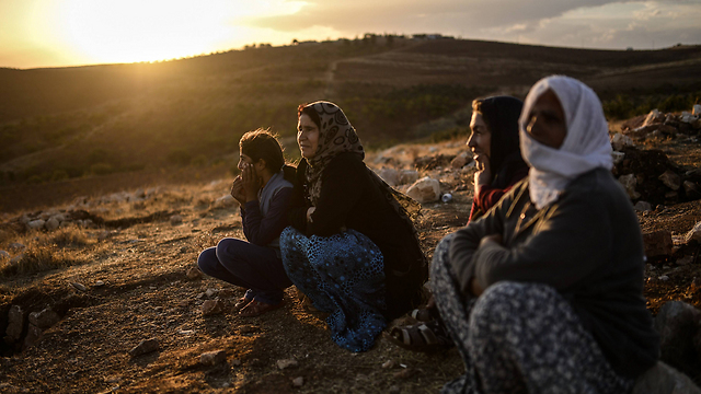 פליטים כורדים צופים בקרבות באזור הגבול עם טורקיה (צילום: AFP ) (צילום: AFP )