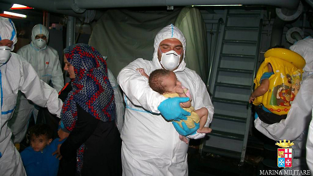 משפחות מהגרים מטופלות ע"י צבא איטליה (צילום: AFP PHOTO / MARINA MILITARE) (צילום: AFP PHOTO / MARINA MILITARE)