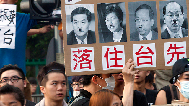Hong Kong protesters hold up photos of leaders with Hitler-like moustache (Photo: EPA)