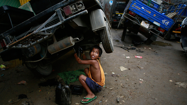ביסווה גורונג, בן 7, עובד במוסך מכוניות בגוואטי                        (צילום: AP) (צילום: AP)