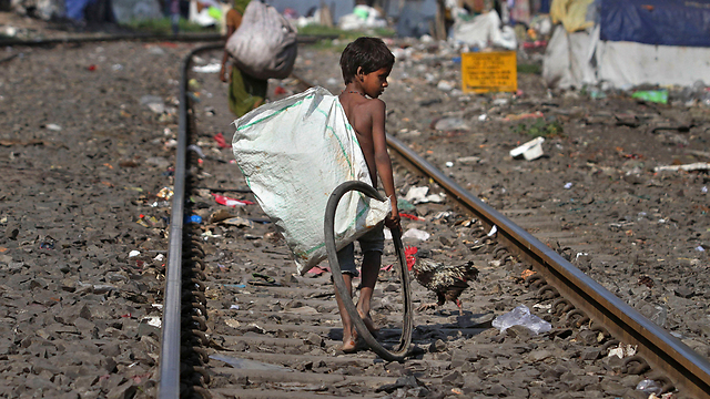 ילד עובד באיסוף סמרטוטים ובגדים בגוואטי (צילום: AP) (צילום: AP)