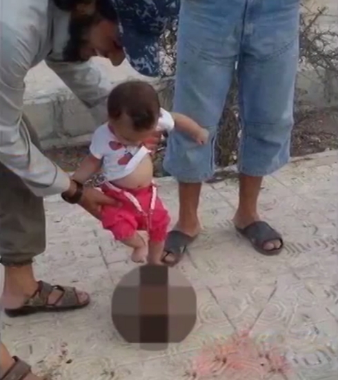 מעזע: האב מחזיק את בתו הפעוטה בעודה בועטת בראש הערוף ברחוב ()