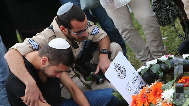 Sahar Shiloni kneels at the grave (Photo: Alex Kolomoisky)