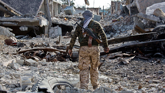 Kurdish fighter walks in ruins of Kobani (Photo: AP)