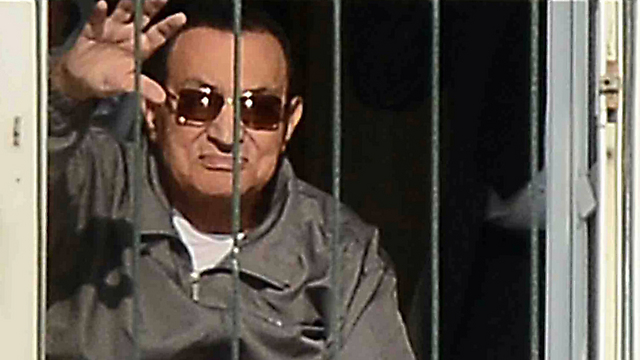 Mubarak waving at his supporters from his room in the military hospital in Cairo (Photo: AP)