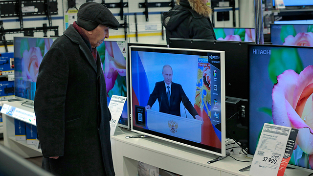 אזרח רוסי חולף על פני טלוויזיה המשדרת את נאומו של פוטין בחנות (צילום: AP) (צילום: AP)