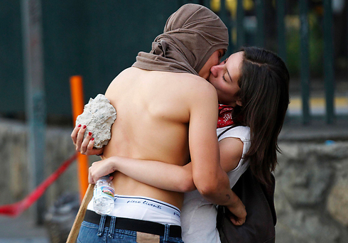 פעילי מחאה נגד הממשלה מתנשקים בלב המהומות בוונצואלה. צילום: כריסטיאן ורון (צילום: רויטרס) (צילום: רויטרס)