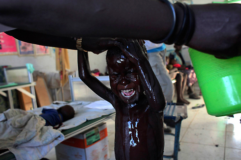 ילד הסובל מתת-תזונה בדרום סודן עובר מקלחת. צילום: אנדראה קמפנו (צילום: רויטרס) (צילום: רויטרס)