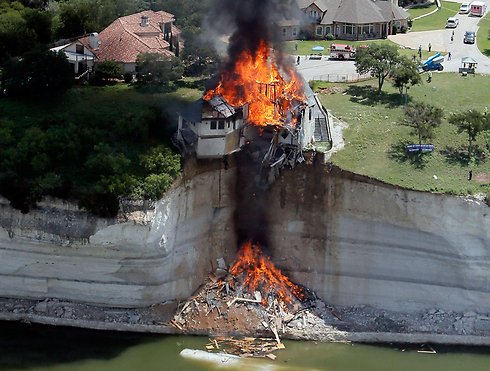 בטקסס קרס צוק שעל ספו ניצב בית. בלית ברירה, הבית הוצת לאחר מכן בכוונה, וברנדון ווייד תיעד את רגעיו האחרונים (צילום: רויטרס) (צילום: רויטרס)