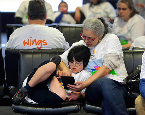 מוניקה סנג'ור קוראת עם בנה, פטסי אוי, בן 11, בזמן ששניהם מחכים בשער העלייה למטוס (צילום: AP) (צילום: AP)
