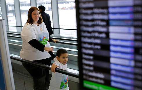 ג'ניפר לנגלי מלווה את בנה, אליוט טילמן בן ה-4, על המסוע בנמל התעופה (צילום: AP) (צילום: AP)