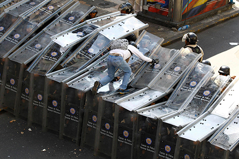 מפגין נועז מטפס על חומת שוטרים ומגנים בהפגנה בוונצואלה (צילום: רויטרס) (צילום: רויטרס)