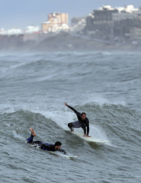 Palestinians Mohammed Abu Jayyab, 41, and Ahmed Abu Hasira, 35, surf at the beach of Gaza City (Photo: AP) (Photo: AP)