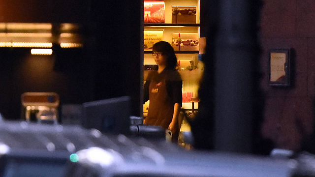 עובדת הקפה, בת ערובה, מכבה את האור בהוראת המחבל כנראה (צילום: AFP / CHANNEL SEVEN) (צילום: AFP / CHANNEL SEVEN)