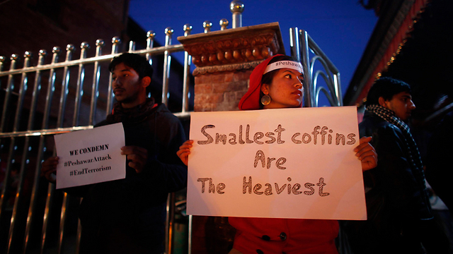 "ארונות הקבורה הקטנים ביותר - הם גם הכבדים ביותר". מפגינה אוחזת שלט בנפאל (צילום: AP) (צילום: AP)