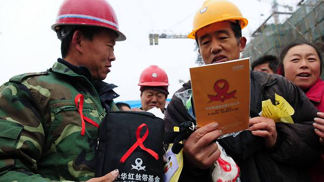 פועלים סינים עם מוצרים להעלאת המודעות לאיידס ו-HIV (צילום: AFP) (צילום: AFP)