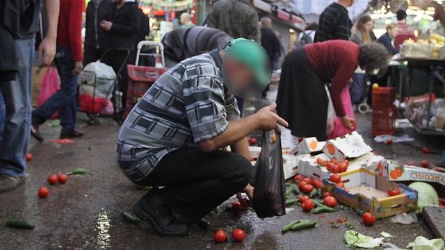 People collect food from ground in Carmel Market in Tel Aviv (Photo: Ido Erez)