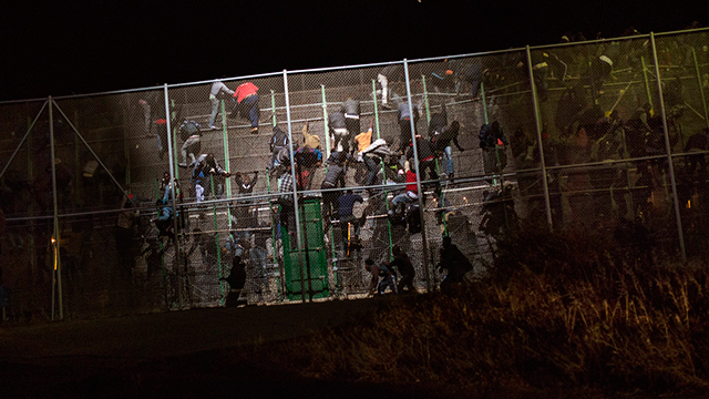 מהגרים אפריקנים מטפסים באישון ליל על גדר ההפרדה בין מרוקו לשטח אפריקני בשליטת ספרד, וכך מסתננים לתוך תחומי האיחוד האירופי. צילום: סנטי פלסיוס (צילום: AP) (צילום: AP)