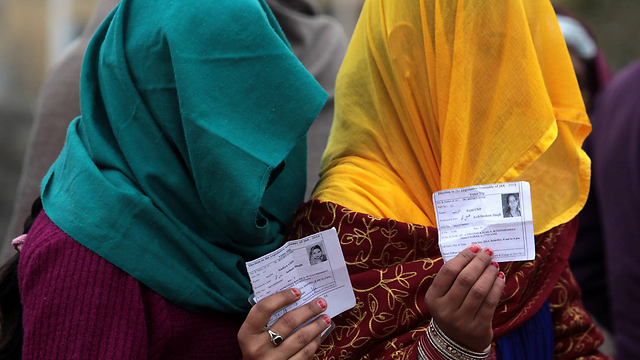 נשים הודיות מציגות את כרטיסי הבוחר שלהן בתור לקלפי בכפר סאטירן, הנמצא במרחק של 30 קילומטרים מהעיר ג'אמו. הבוחרים התבקשו לבחור את נציגיהם באסיפה הכללית של מדינת ג'אמו וקשמיר (צילום: AFP) (צילום: AFP)