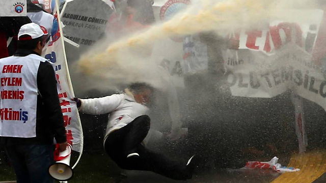 אדם נופל לקרקע לאחר ששוטרים יורים זרנוקי מים כדי לפזר מפגינים באנקרה המוחים נגד מדיניות החינוך של הממשלה הטורקית (צילום: AFP) (צילום: AFP)