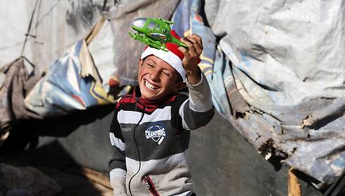 פליט סורי במחנה פליטים בלבנון מתרגש מצעצוע שחילק ארגון צדקה (צילום: רויטרס) (צילום: רויטרס)