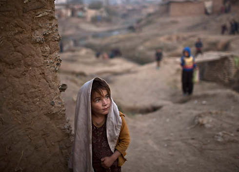 סאיימה נאסיב, פליטה אפגנית בת ארבע, עומדת בפתח בית הבוץ של משפחתה בשכונת עוני בפאתי איסלאמבד, בירת פקיסטן (צילום: AP) (צילום: AP)