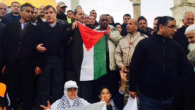 MK Ahmad Tibi waves the Palestinian flag during a march at al-Aqsa mosque in January 2015 (Photo: Tamer Abidat)