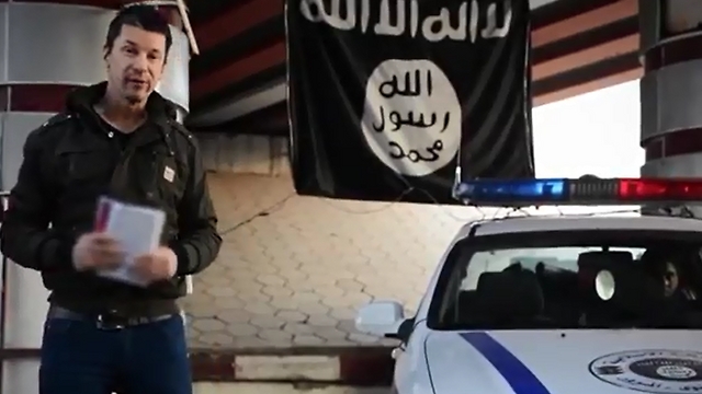 קנטלי בסרטון במוסול לצד ניידת משטרה של דאעש ()