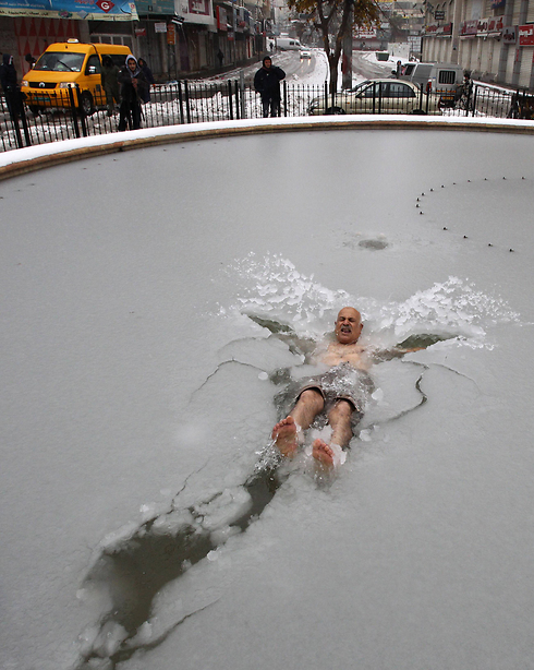 Palestinian man swims in a pond covered with ice in Hebron (Photo: AFP) (Photo: AFP)