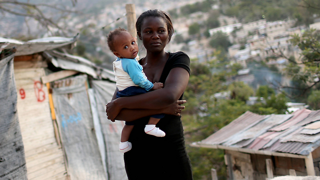 תושבת פורט או-פרינס עם בנה התינוק במקום שבו עמד פעם ביתה (צילום: gettyimages) (צילום: gettyimages)