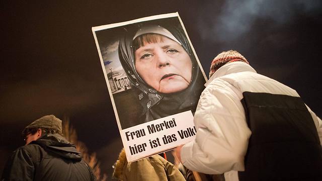 שלט עם תמונתה הערוכה של מרקל, עטויה בכיסוי ראש איסלאמי, בהפגנה בדרזדן (צילום: EPA) (צילום: EPA)